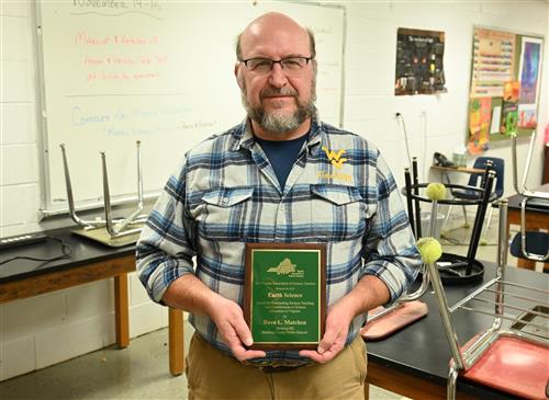  Earth science teacher Dave Matchen holds up his engraved plaque